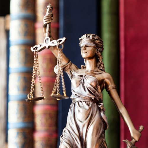 vrouwe justitia met wetboeken op achtergrond-500x
